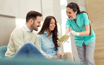 Happy couple and dental professional discussing insurance coverage