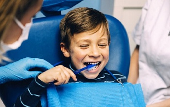 little boy brushing teeth in dental chair