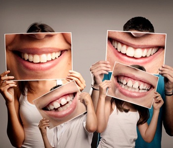 family holding photos of smiles in front of their faces