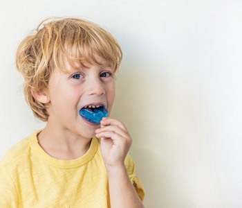 little boy inserting mouthguard 