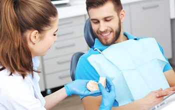 A male patient looking at a tooth mold his dentist is holding