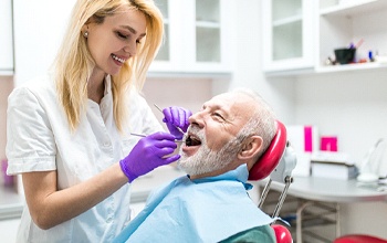 A dentist checking an older man’s teeth and gums