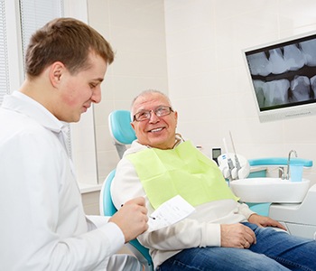An older man listening as his dentist explains the process of receiving dentures