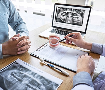 A dentist discussing with a male patient the cost of dentures