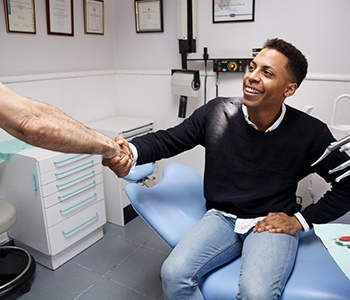 Smiling patient and dentist discussing cost of dental emergencies in Carrollton