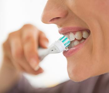 Closeup of patient preventing dental emergencies in Carrollton by brushing 