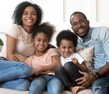 family smiling and sitting on a couch