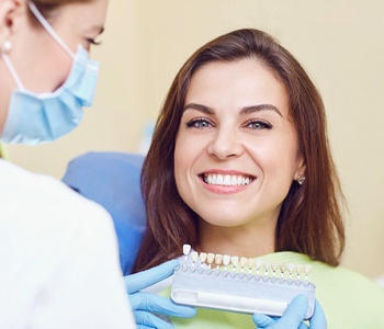 dentist matching patient’s tooth color to a chart