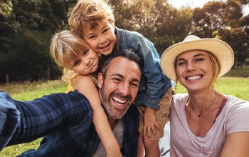 smiling family in front of trees 