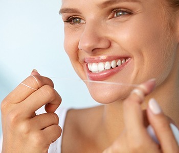 Woman flossing teeth in Carrollton