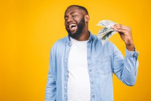 man holding money for CareCredit for cosmetic dental treatment