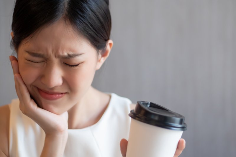 Woman experiencing tooth sensitivity from morning coffee