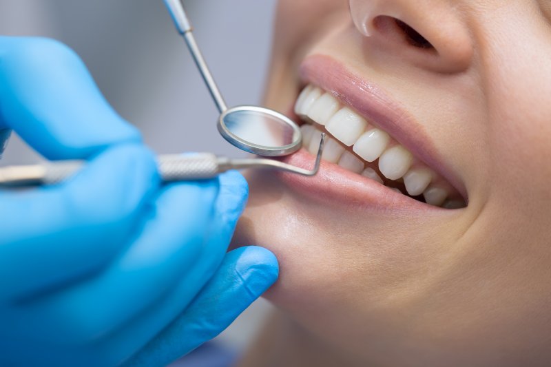 Dentist using dental tools to examine patient's teeth