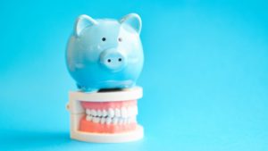 light blue piggy bank sitting on top of a set of dentures 